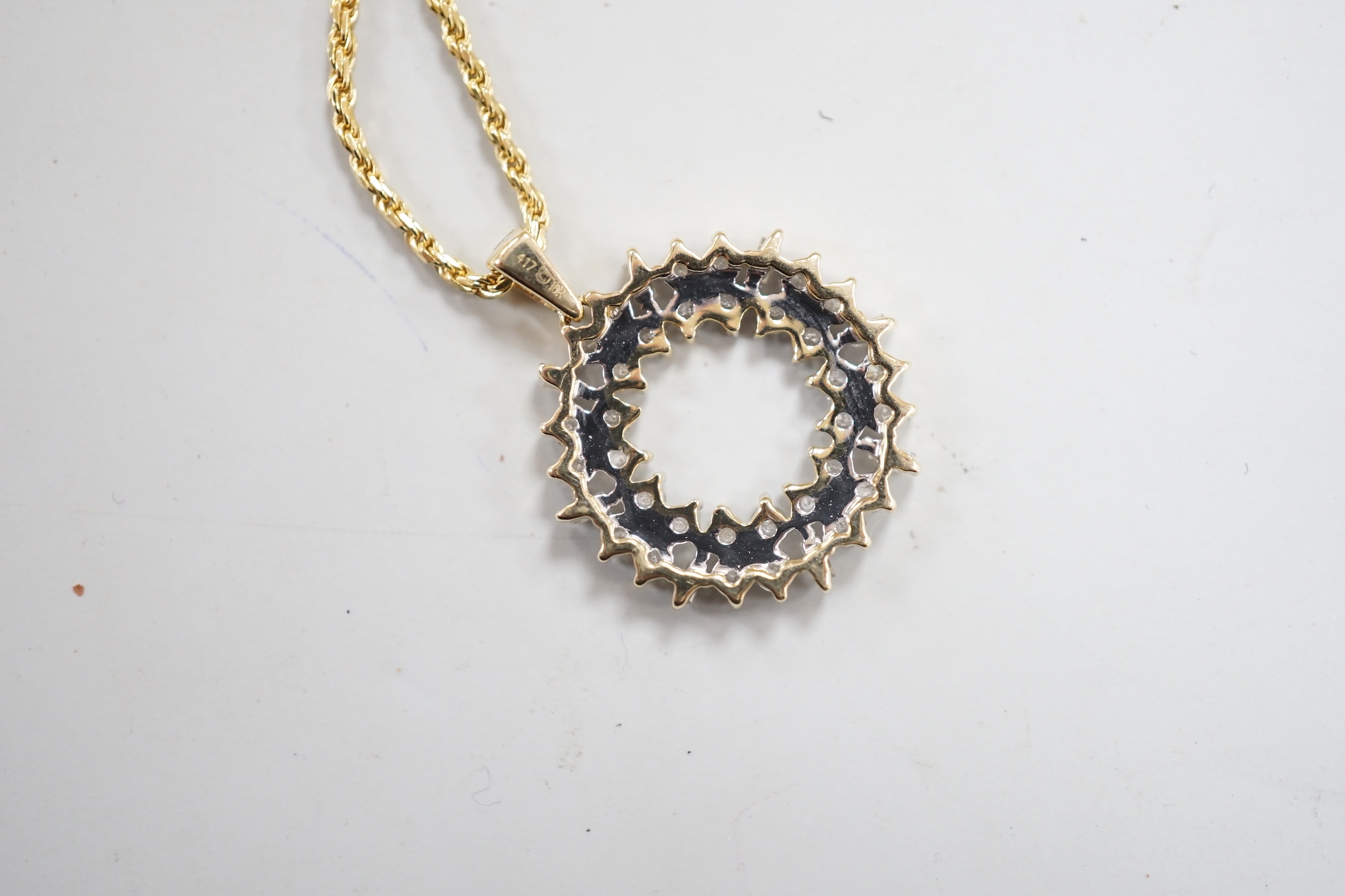 A modern 9ct gold, baguette and round cut diamond cluster set openwork pendant, diameter 17mm, gross 1.9 grams, on a modern 750 yellow metal fine rope twist chain, 48cm, 5.1 grams.